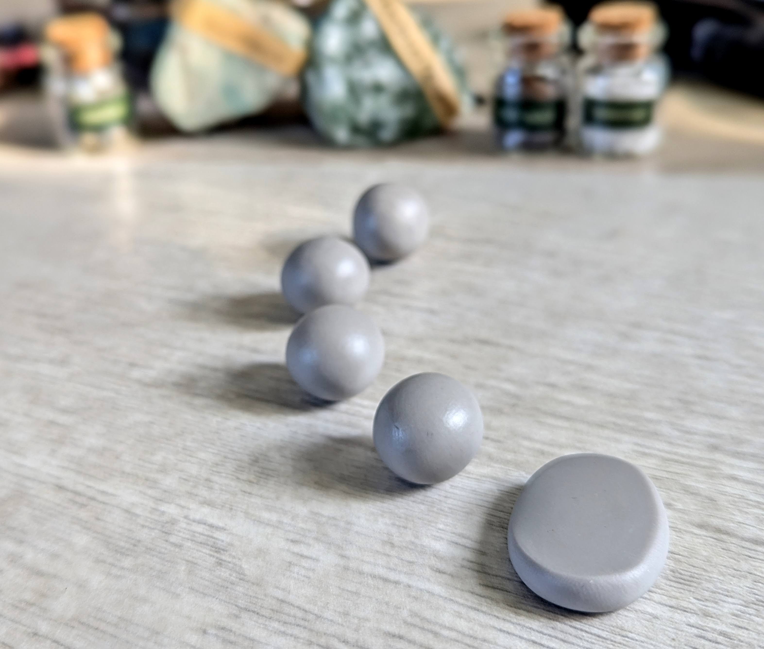 A line of clay, some rolled and one flattened into a rune shape.